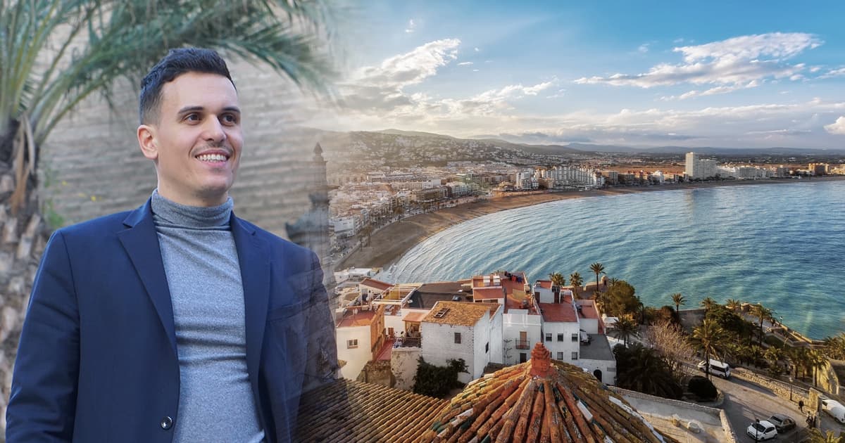 A real estate hunter stands in front of a scenic view of the Spanish coastline, featuring a beach and coastal town