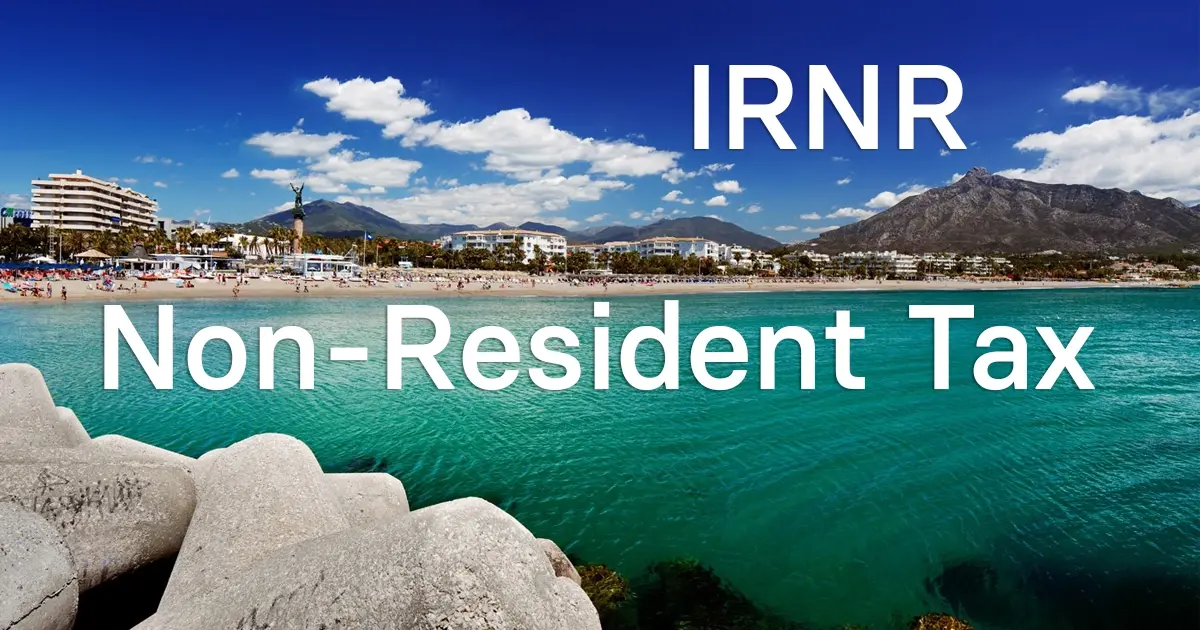 Mediterranean sea with rocky breakwater and cityscape representing IRNR tax for non-residents in Spain