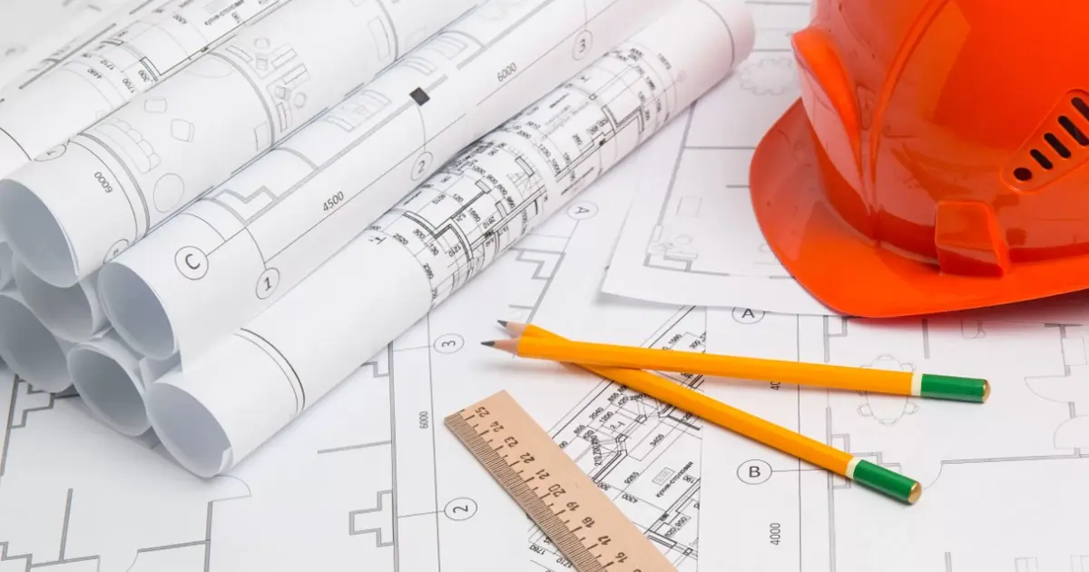 Architectural blueprints with pencils, ruler, and safety helmet, symbolizing Spain's cadastral reference system