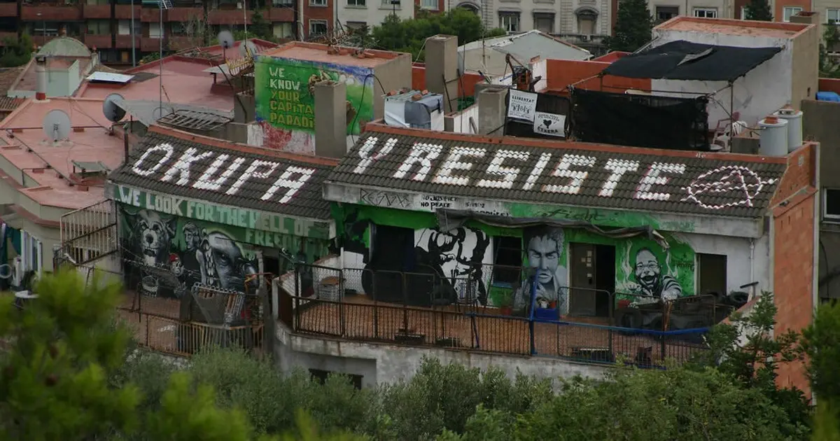 Okupas Occupied building in Spain with graffiti and banner reading 'Okupa y Resiste', symbolizing anti-eviction movement