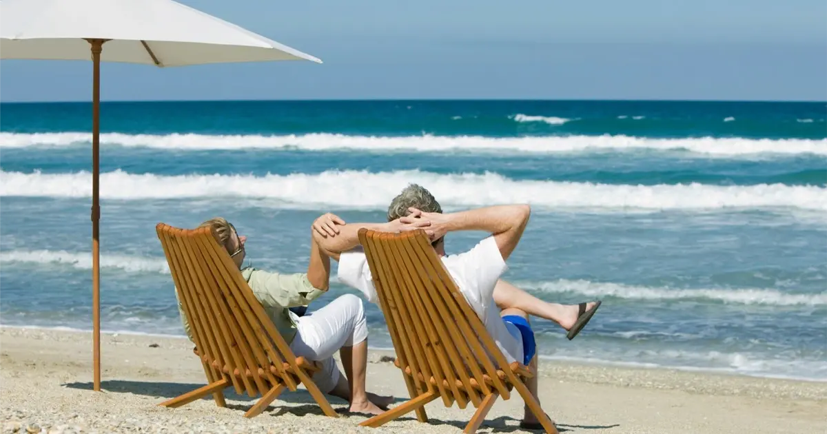 Retired couple relaxing on a sunny beach in Spain, representing lifestyle benefits of Spain retirement in 2025