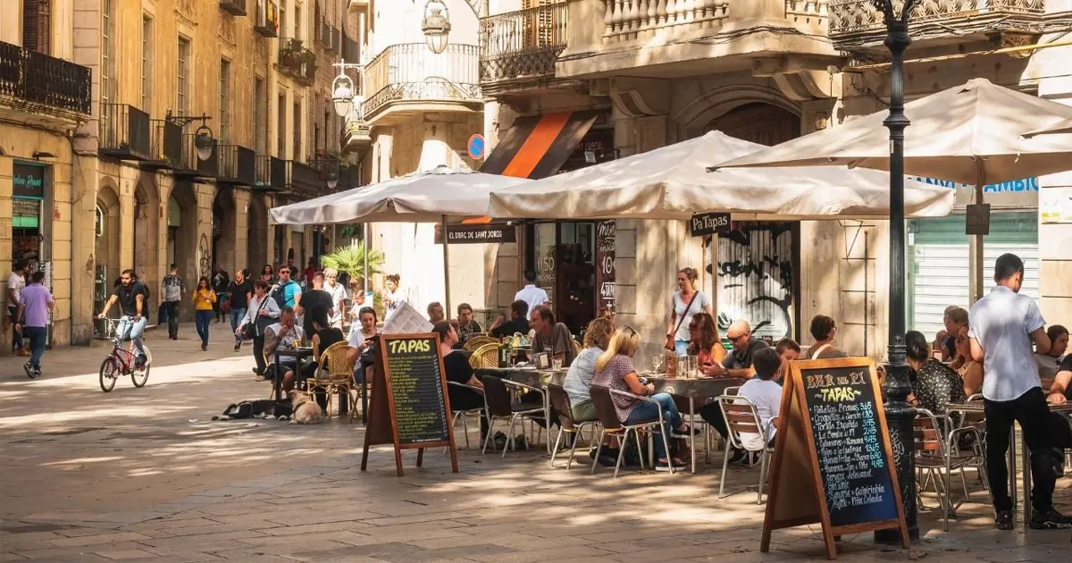 Busy tapas bar terrace in Spain with menu displayed, showing cost of living and restaurant prices