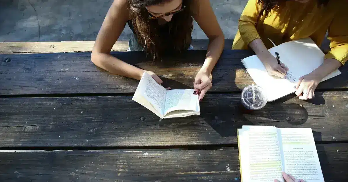 Students studying outdoors with books and notes, representing the Spanish school system.